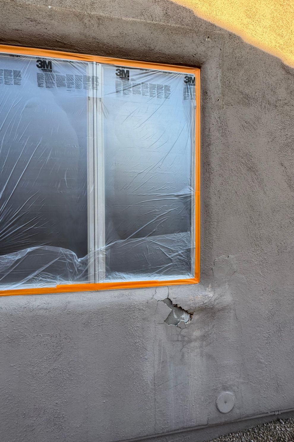 A window is covered in plastic while being painted.