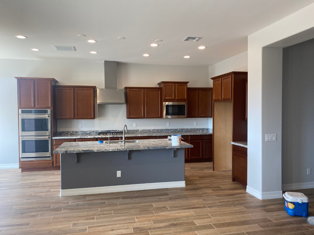 A kitchen with wooden cabinets , granite counter tops , stainless steel appliances and a large island.