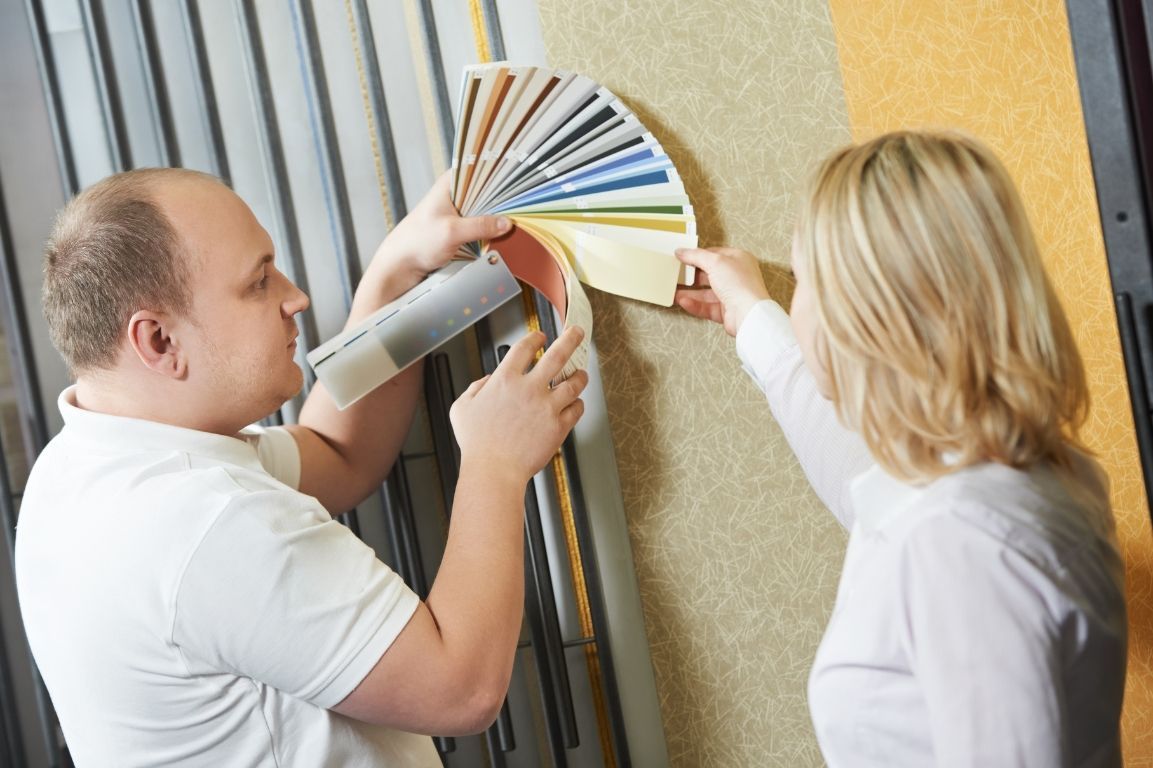 A man and a woman are looking at paint samples on a wall.