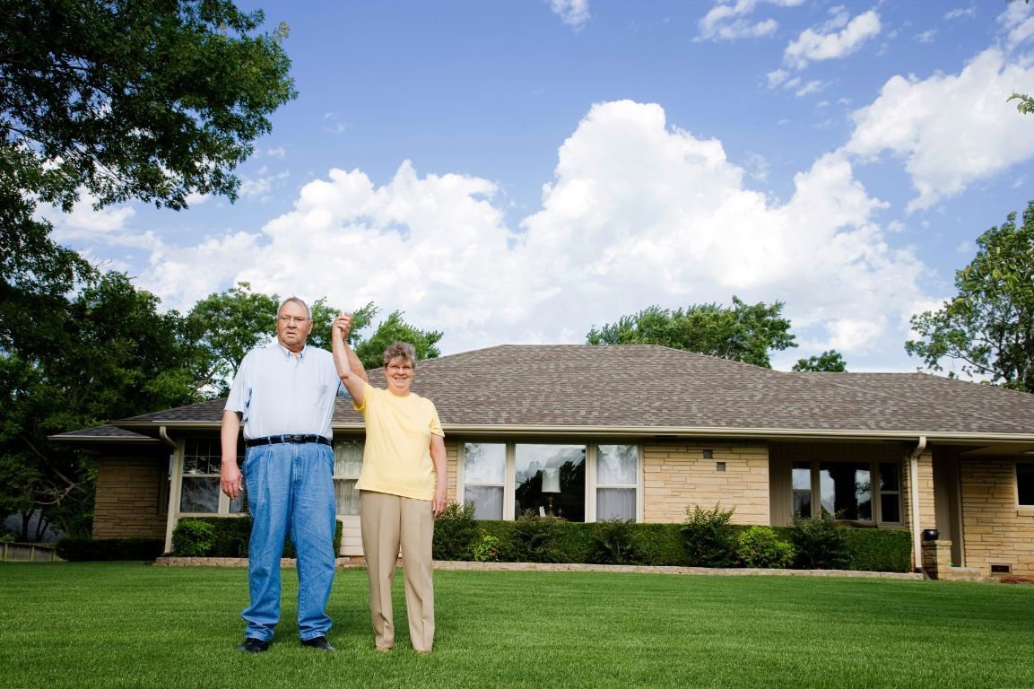 A man and a woman are standing in front of a house.