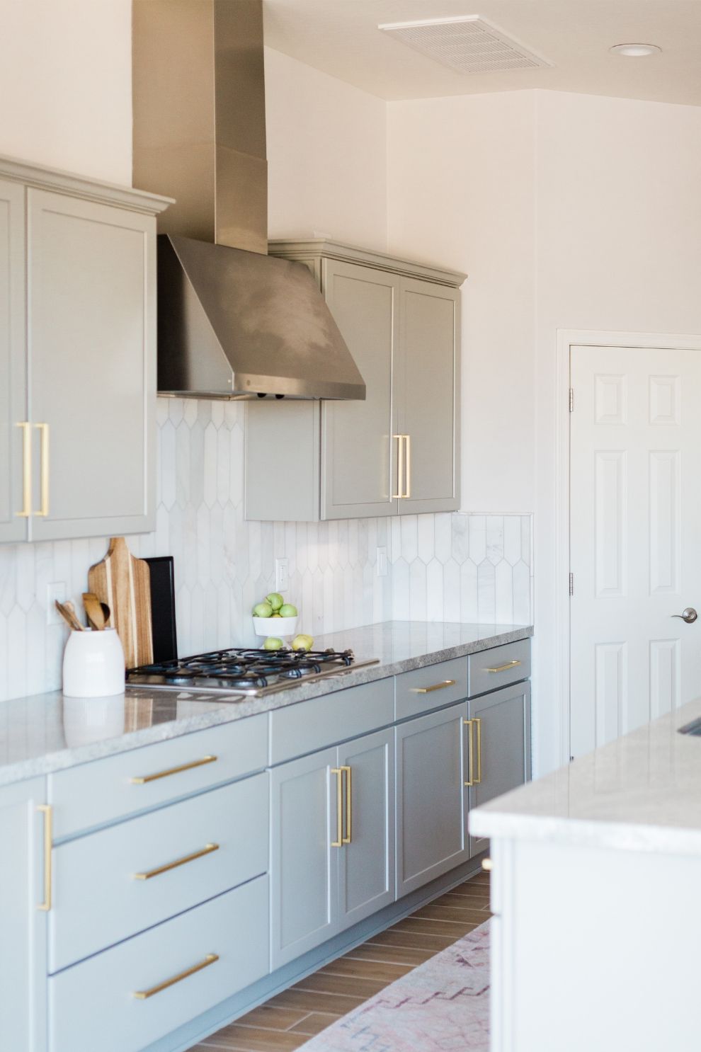 A kitchen with gray cabinets and stainless steel appliances.