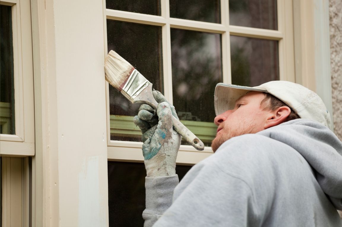 A man is painting a window with a brush.
