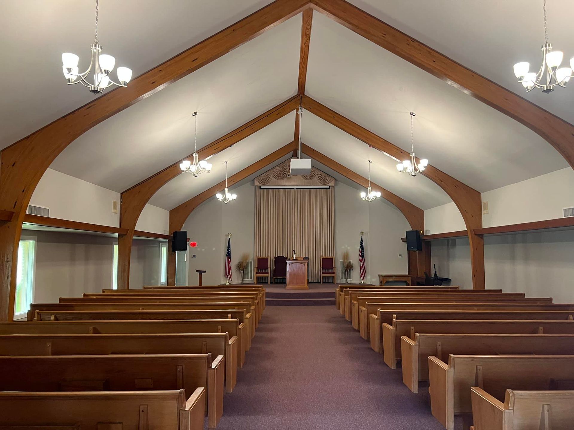 Church interior with wooden pews, vaulted ceiling, and a small altar at the front