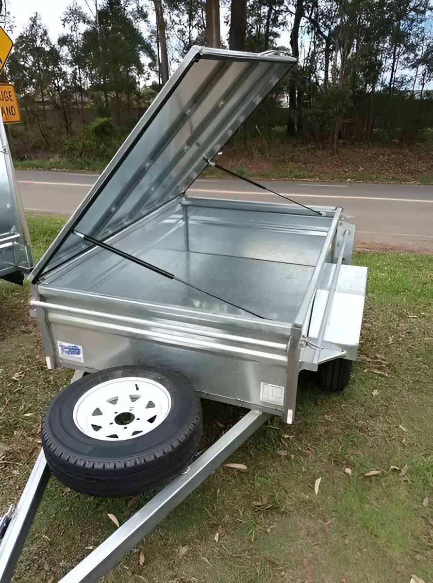 A Newly Trailer With The Lid Open Is Parked On The Grass Next To A Road — Hastings Trailer Centre in Port Kempsey, NSW
