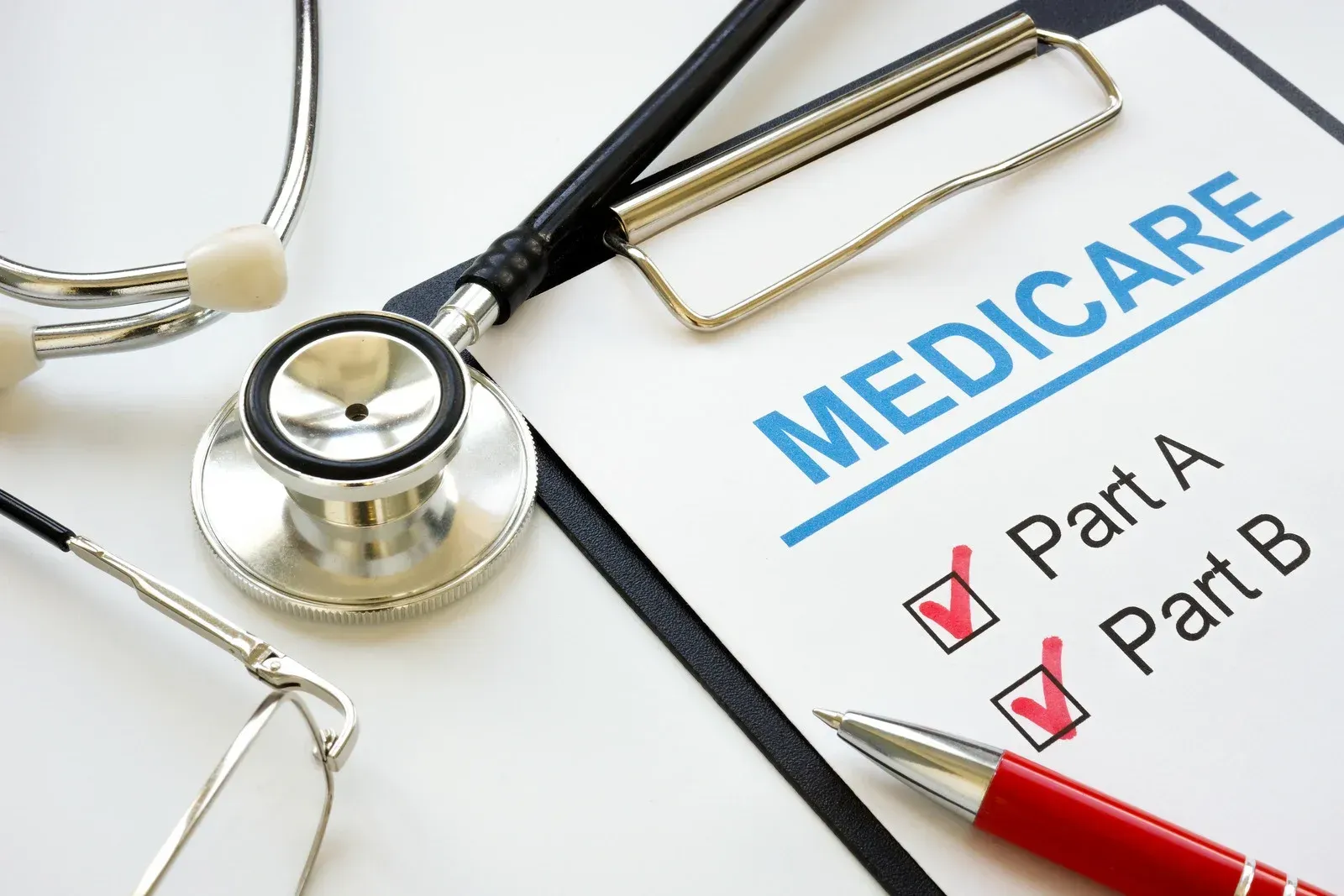 Medicare clipboard with stethoscope and pen; checklist marks Part A and B.