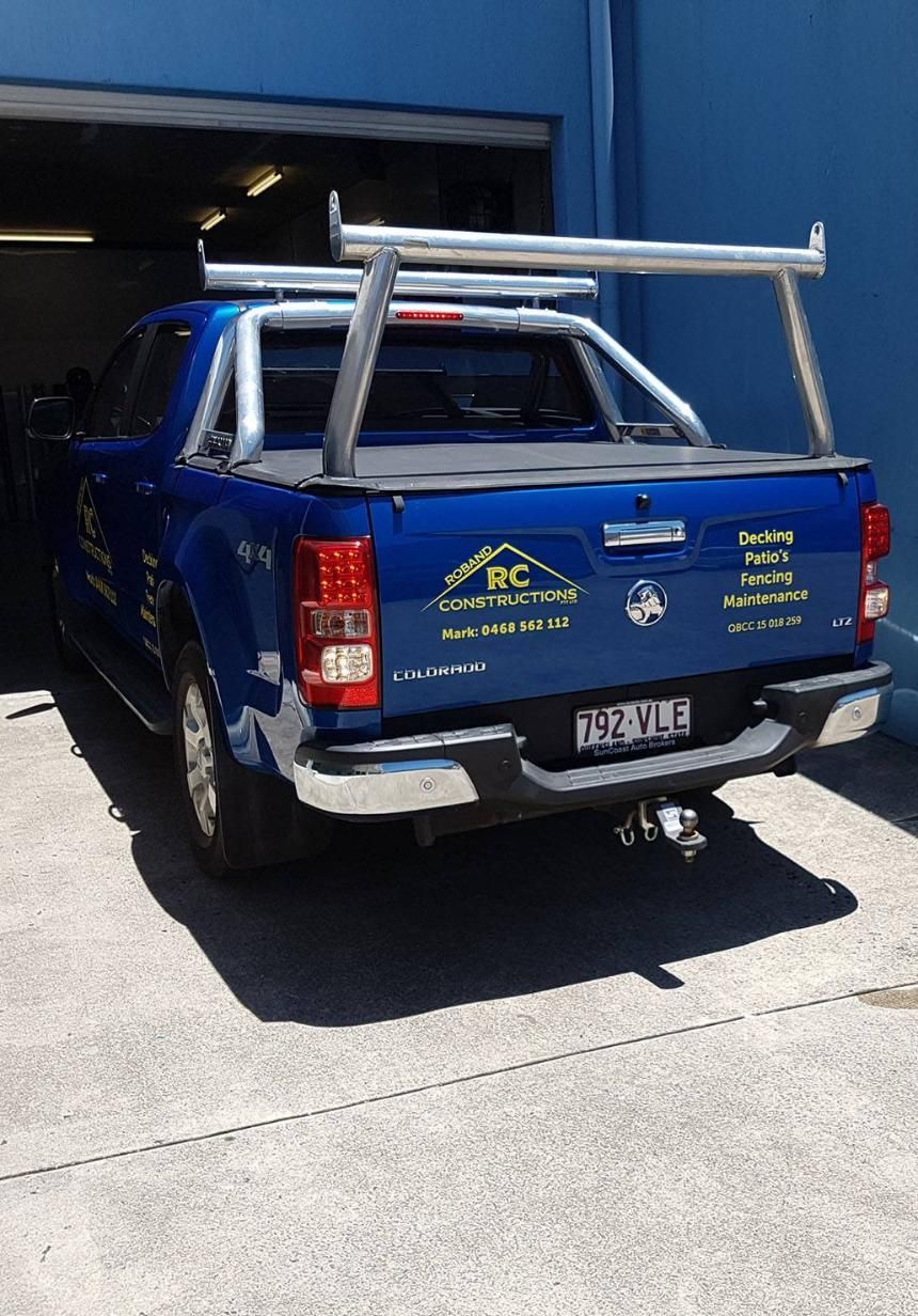 A Blue Truck With a Ladder Rack on the Back is Parked in Front of a Blue Building — Caledonian Colour In Maroochydore, QLD
