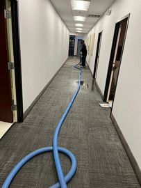 Floor cleaning machine scrubbing white tiled floor. Gray and blue machine.