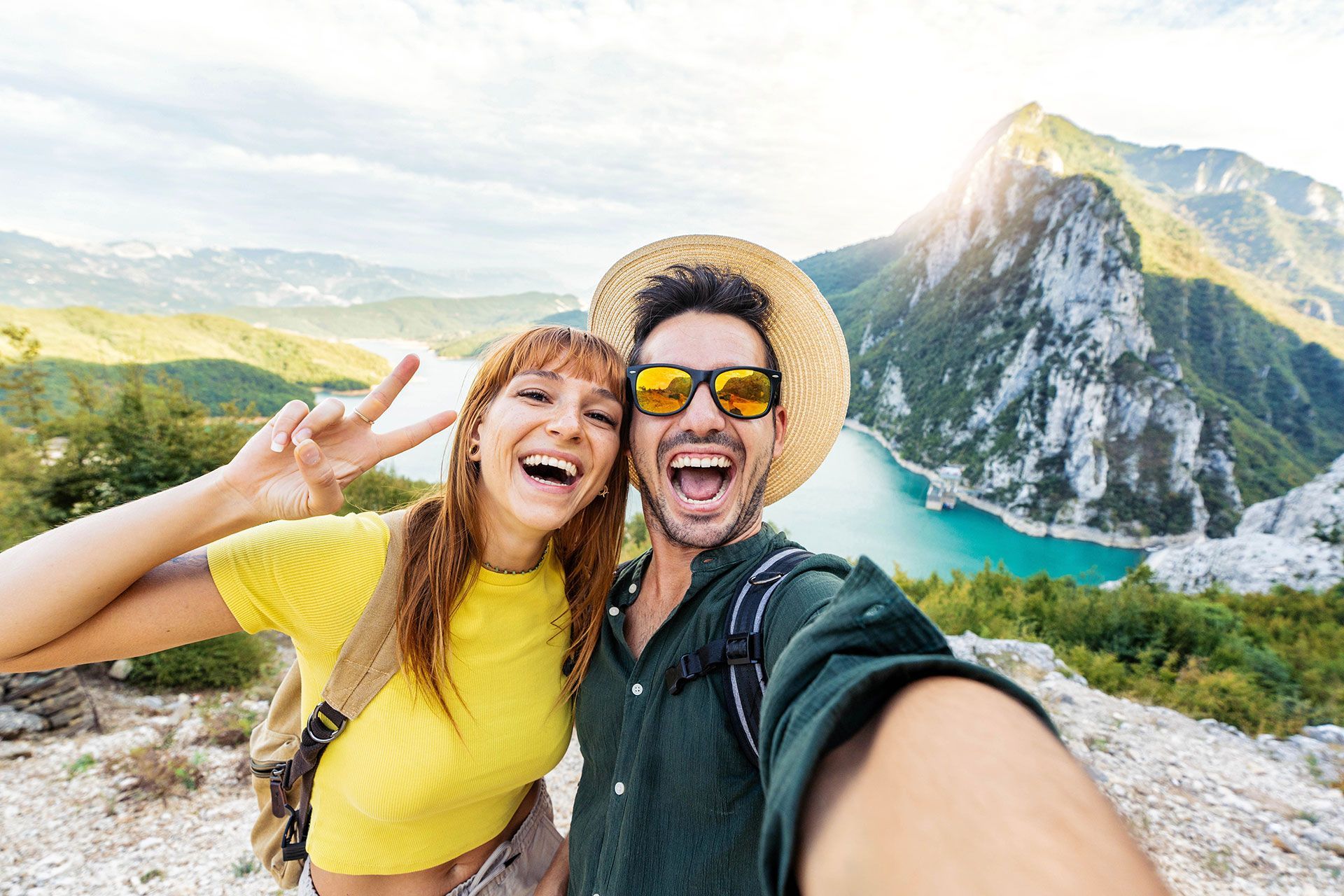 A man and a woman are taking a selfie on top of a mountain.