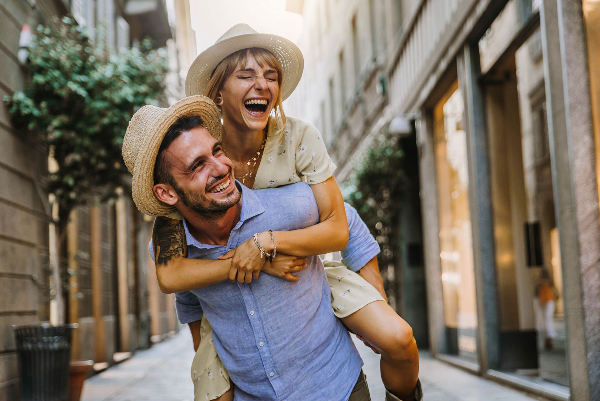 A man is carrying a woman on his back on a city street.