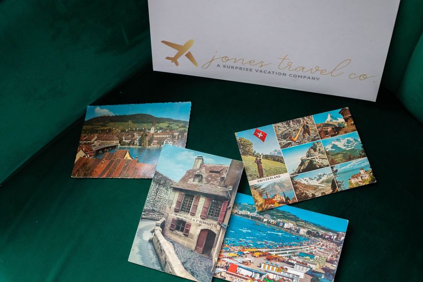 Four postcards are sitting on a green couch in front of a sign that says ' yourtravel.com '