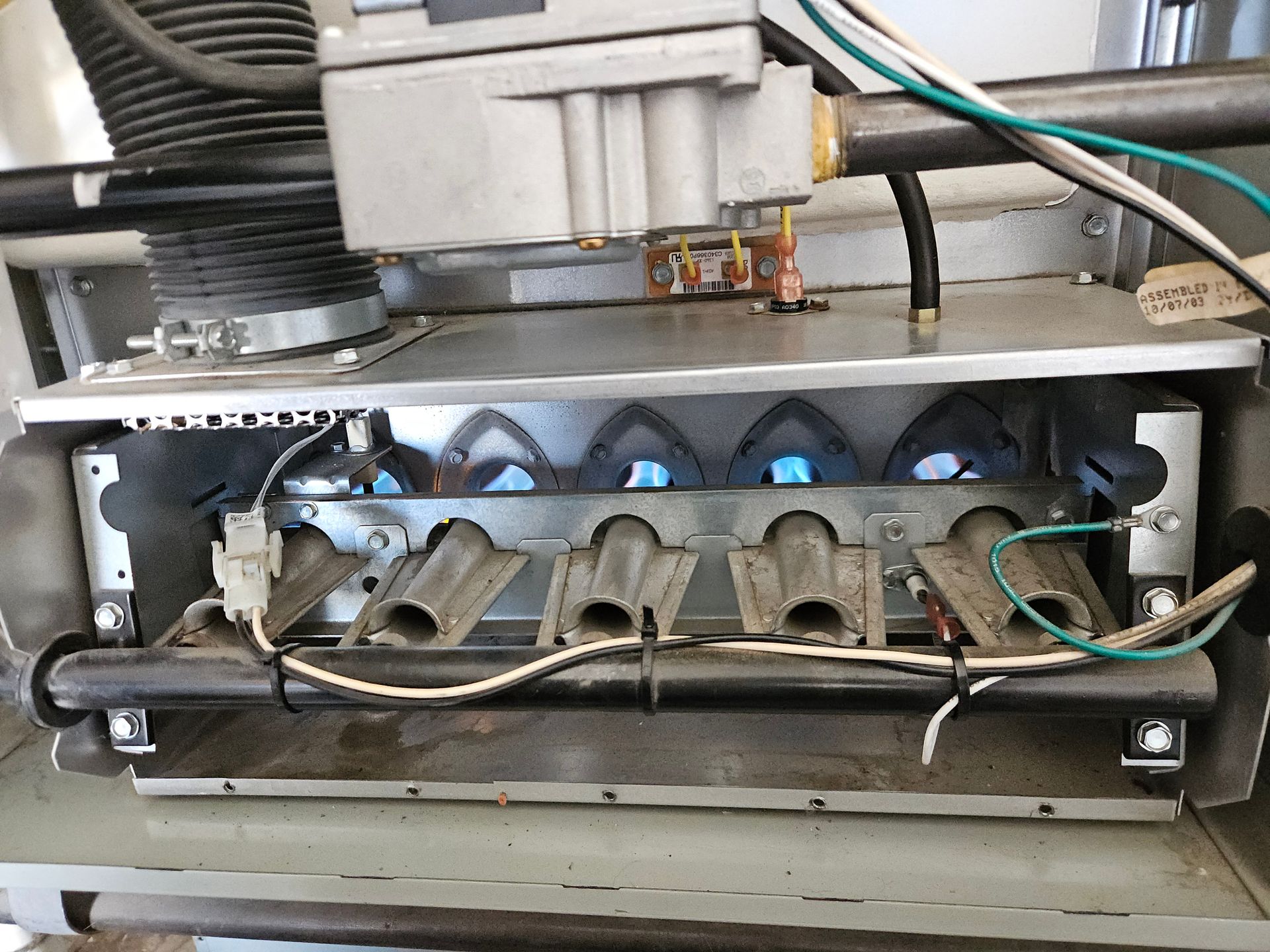 Gas furnace with blue flames, burner tubes, and electrical components.