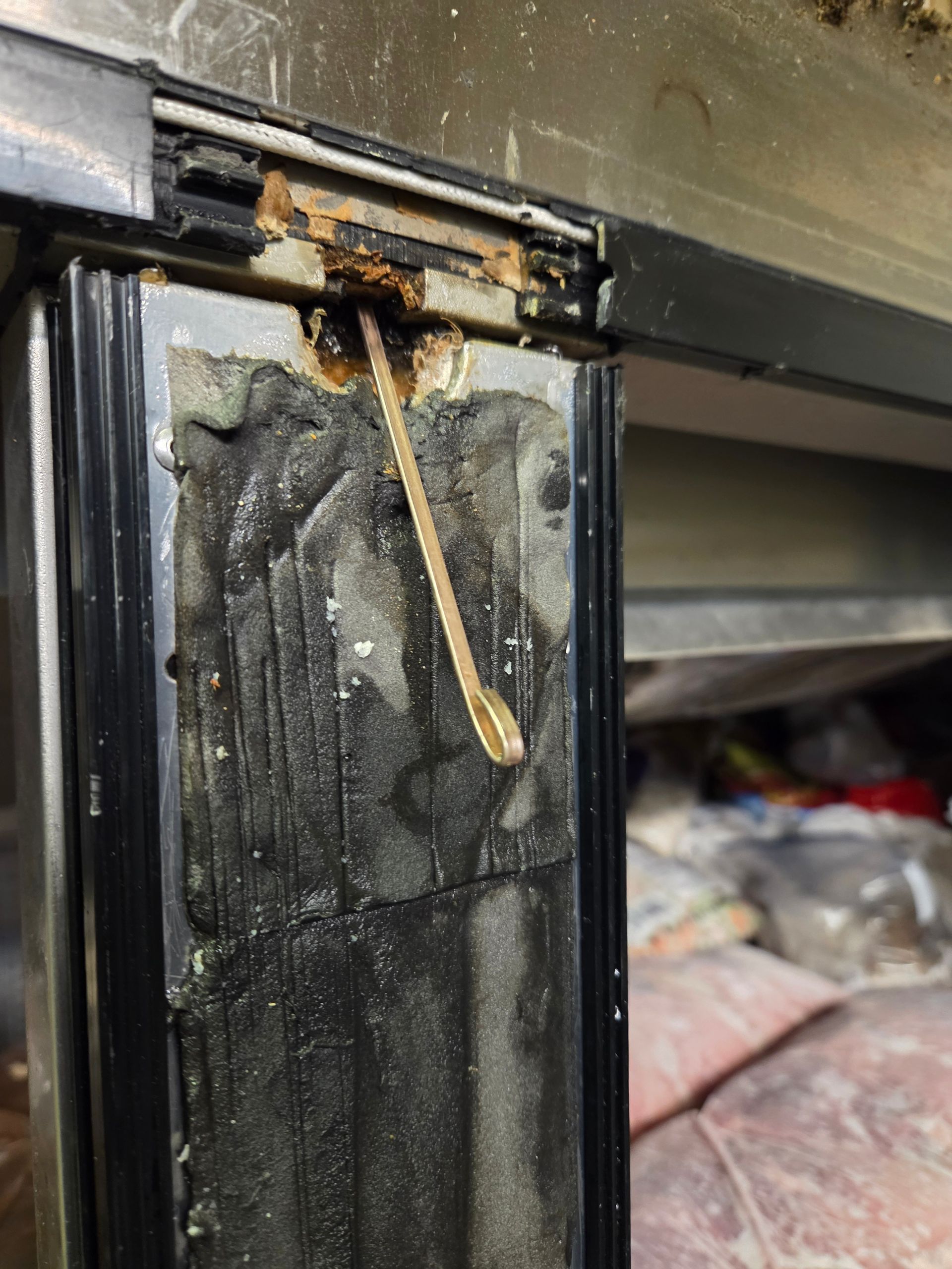 Close-up of a damaged refrigerator door frame, showing a broken pull string and corrosion.