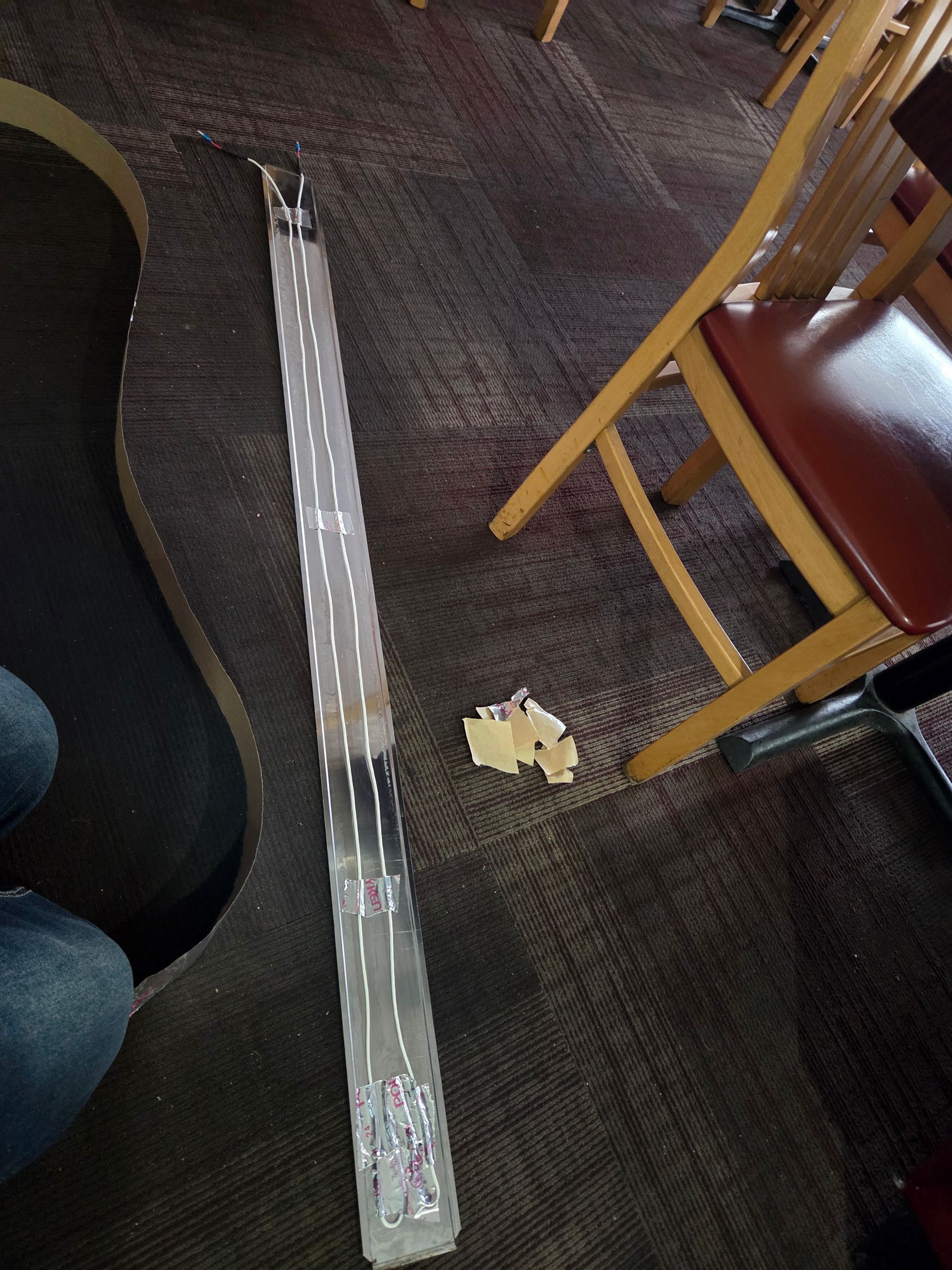 Clear plastic light tube on carpet next to a chair and a small object.