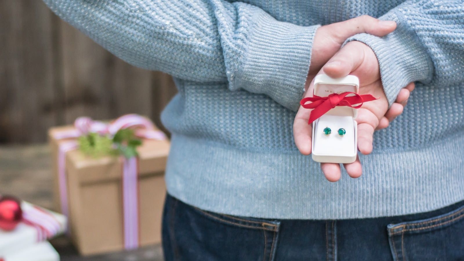 holiday gifts man holding earrings gift behind his back