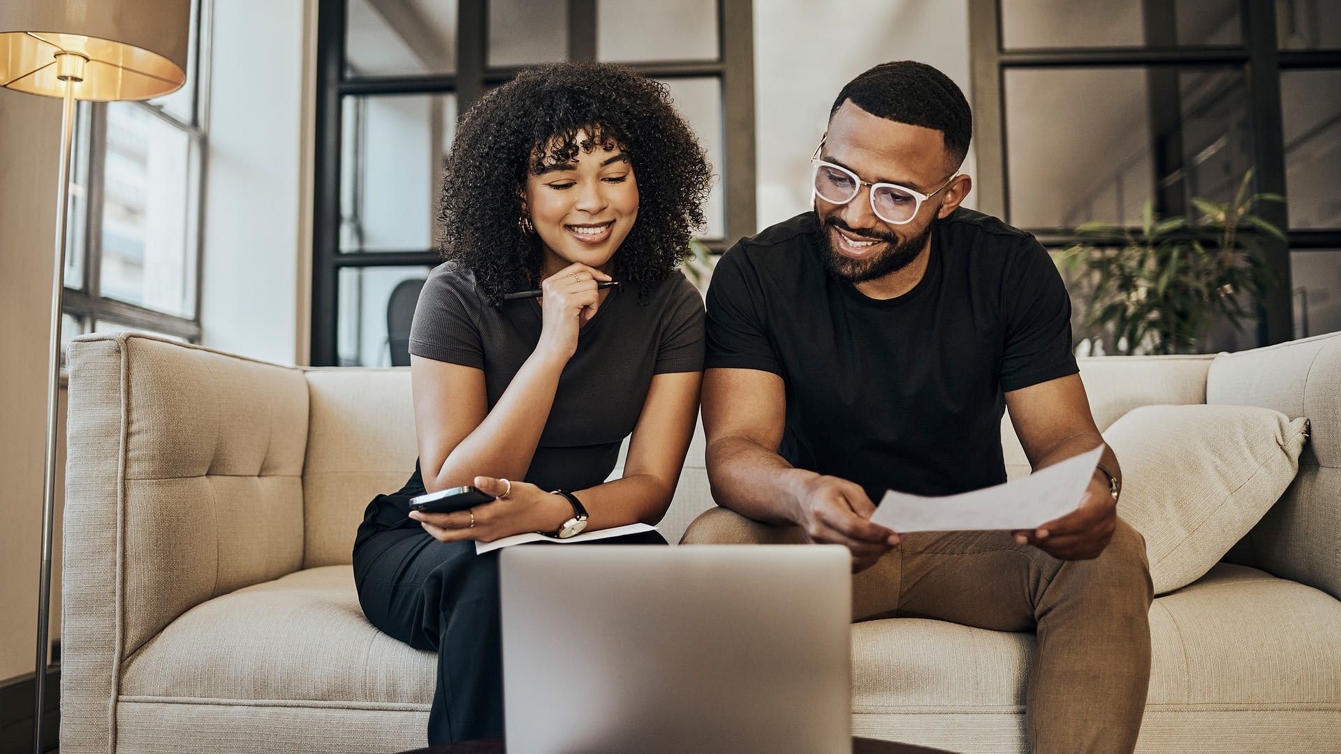 Happy couple smiling at computer Young couple reviewing together