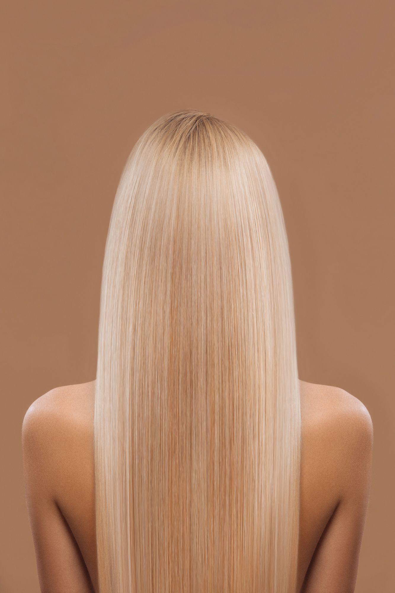 Vista posteriore di una persona con lunghi capelli lisci biondo platino su sfondo marrone.