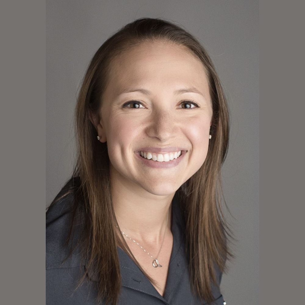 A woman is smiling for the camera and wearing a necklace.