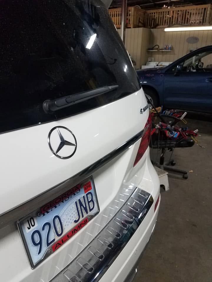 Rear of a white Mercedes SUV with a Utah plate, parked in a garage beside bicycles.