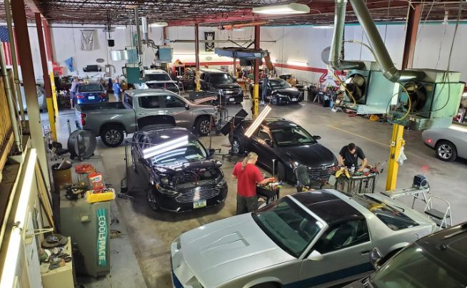 Busy auto repair shop with several cars and mechanics working inside