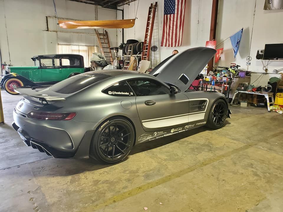 Gray sports car with hood open in a garage workshop