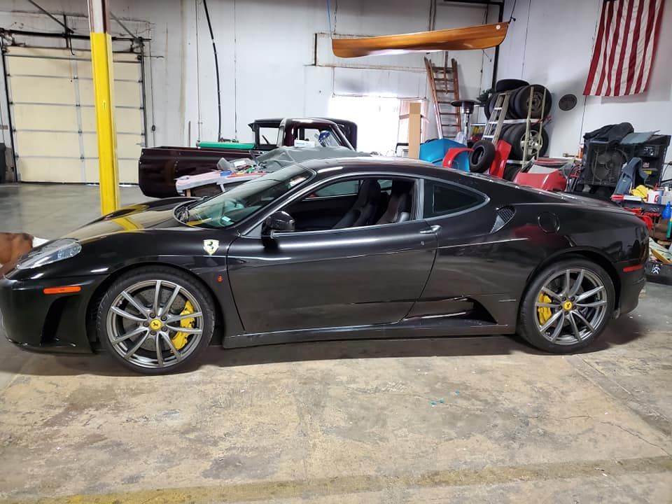 Black sports car in a garage with yellow racing calipers and a rear wing