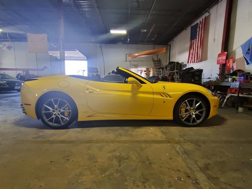 Yellow convertible sports car in a garage, side view with top down
