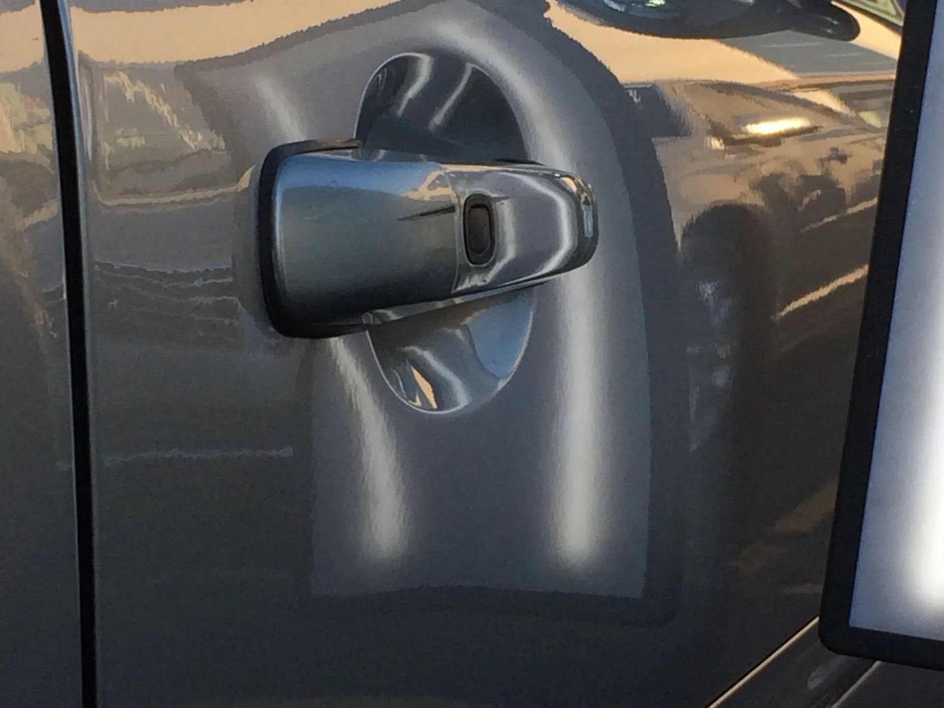 Close-up of a black car door handle on a dark gray vehicle.