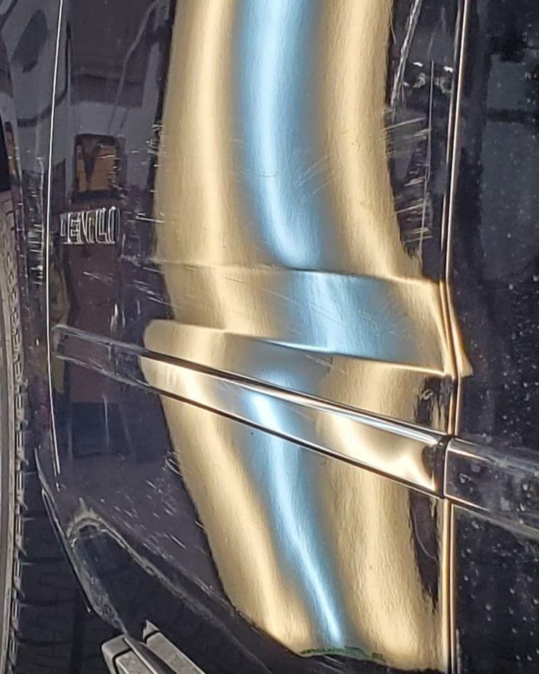 Close-up of a glossy gold and black car side panel with a reflective chrome trim line