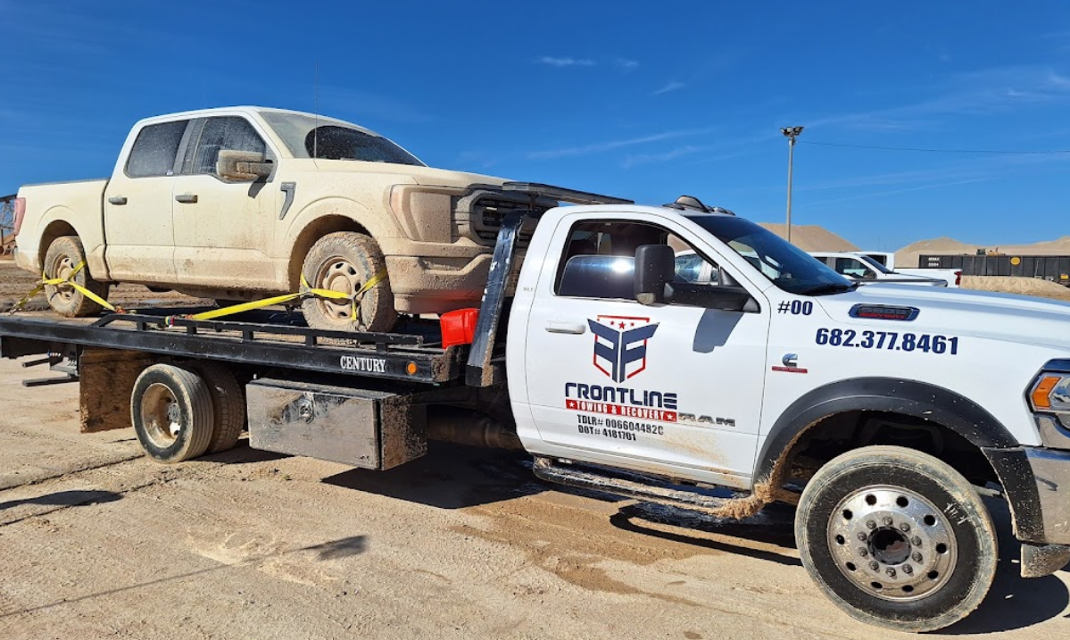 A tow truck is carrying a white truck on the back of it.
