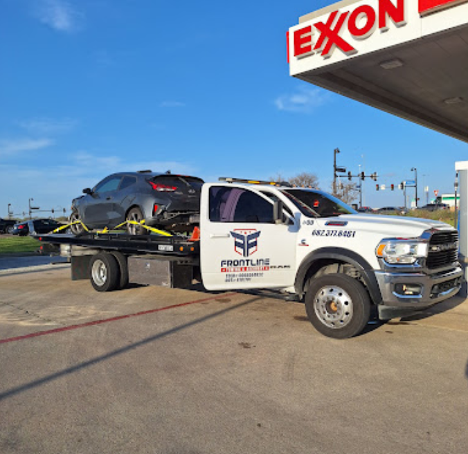 A tow truck is parked in front of an exxon gas station