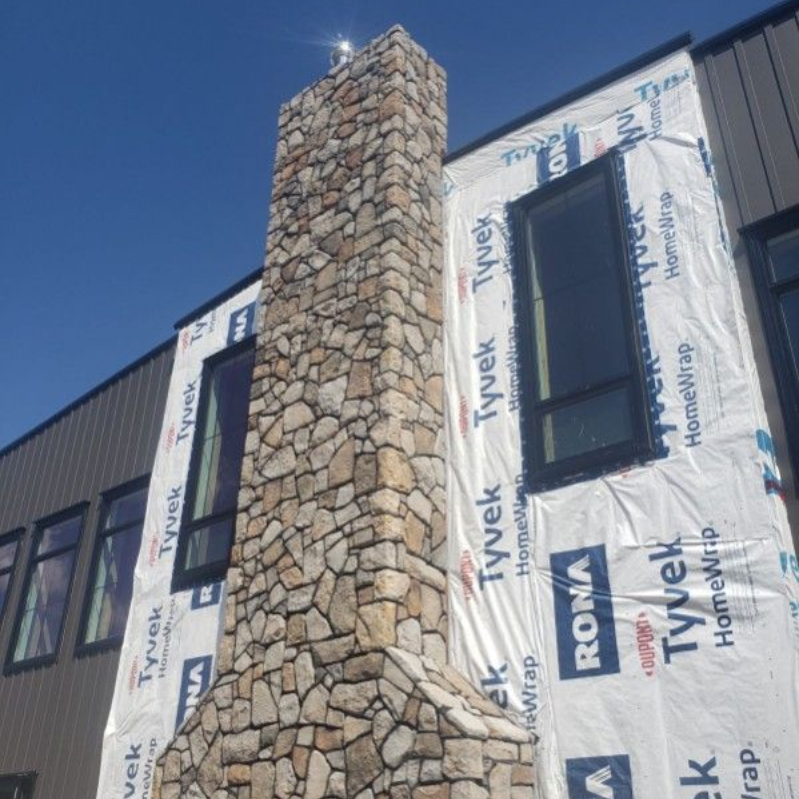 A stone chimney on a house under construction.