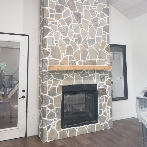 A modern fireplace built into a white stone wall, with a recessed space for a TV and soundbar.