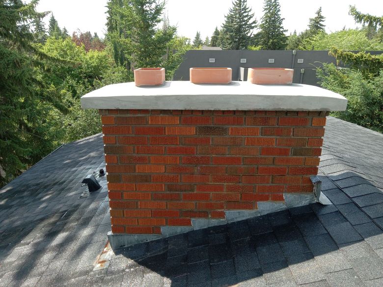Brick wall with arched doorway leading to a patio with a red pot and a ladder.