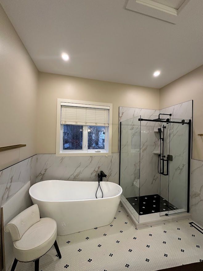 Modern bathroom with freestanding tub, glass shower, white marble walls, and patterned floor tiles