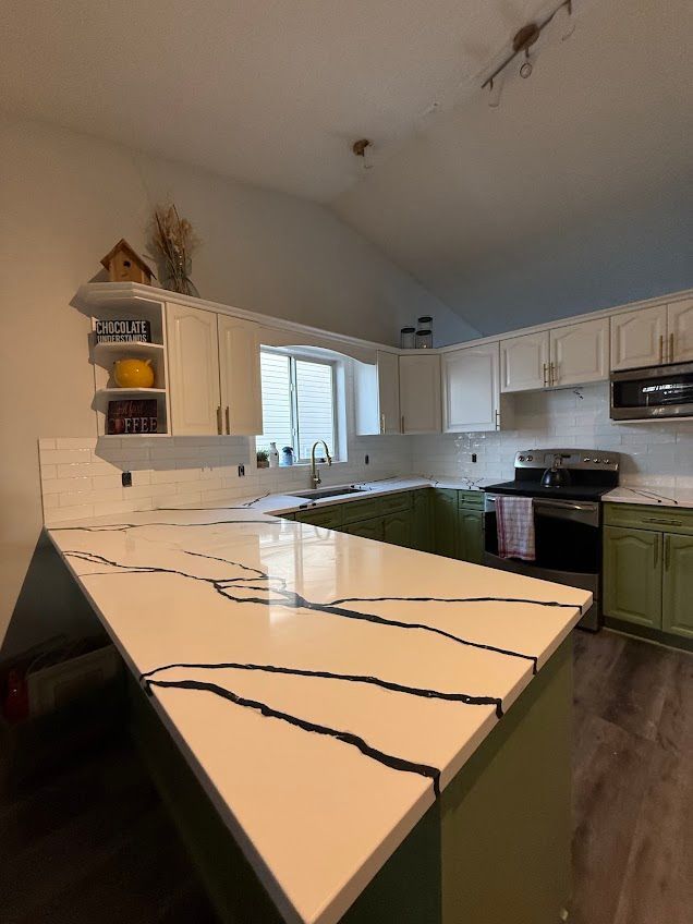 Modern kitchen with white cabinets, black appliances, and a large white island countertop.