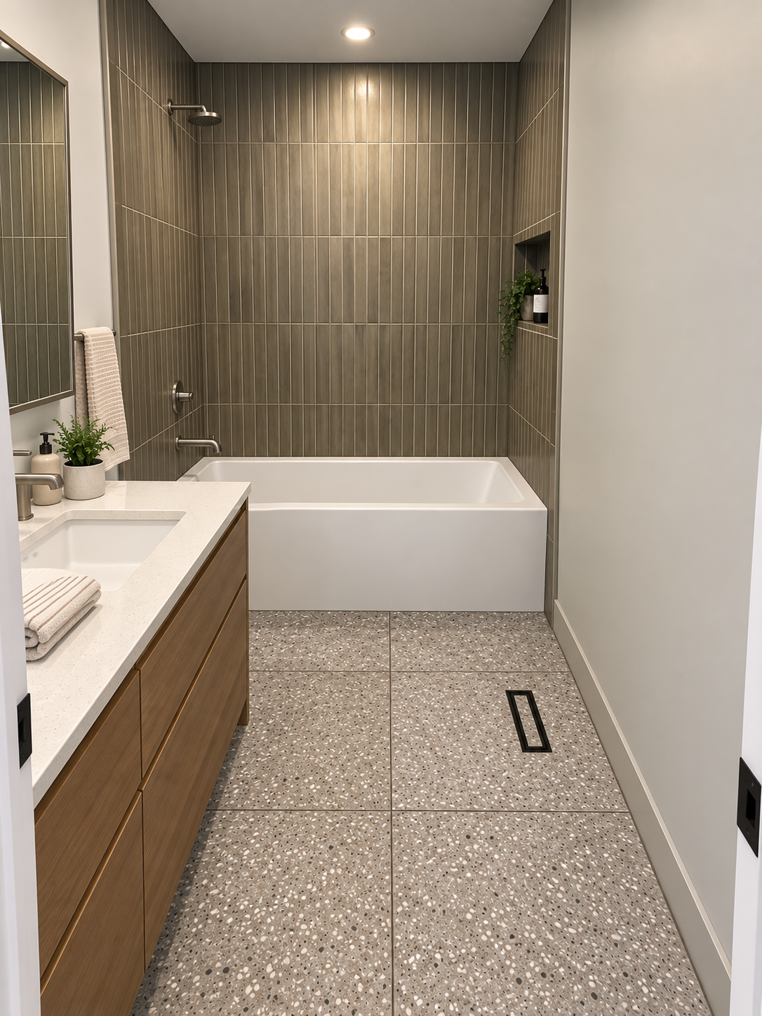 Modern bathroom with wood vanity, white tub, and gray tile floor and walls