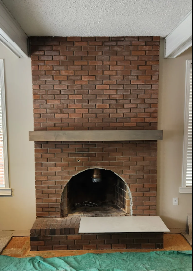 Newly tiled Brick fireplace with arched firebox, wide mantel, and window blinds on both sides.