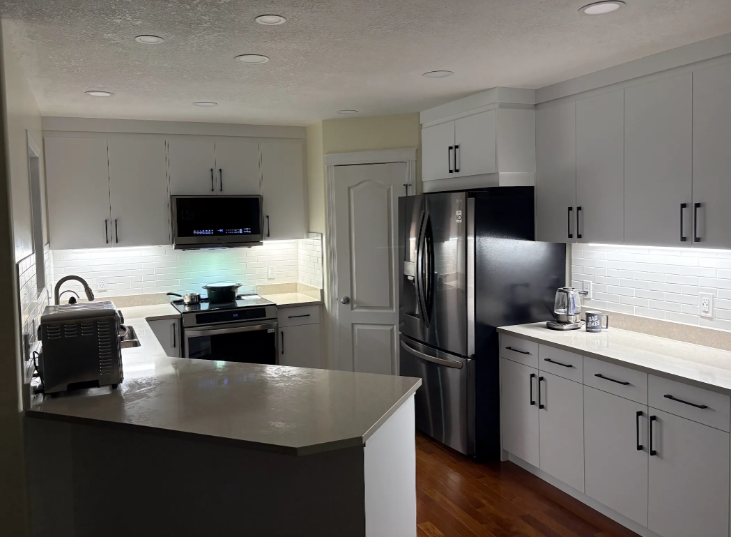 Modern white kitchen with stainless steel appliances, island, and hardwood floors