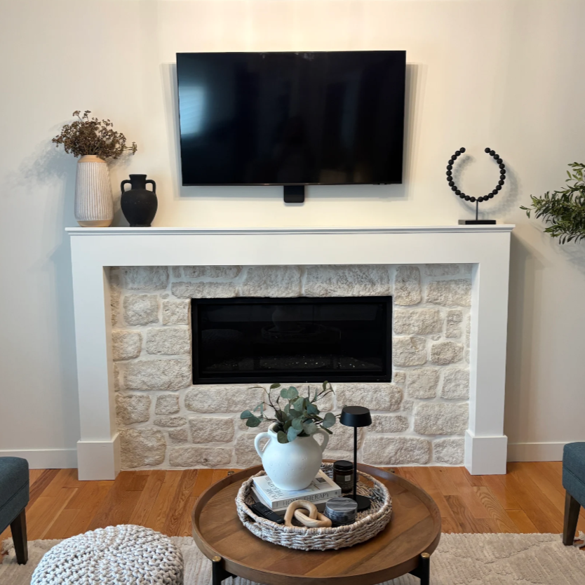 Modern living room with a wall-mounted TV above a stone fireplace and a round coffee table in front