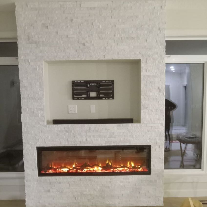 A modern fireplace built into a white stone wall, with a recessed space for a TV and soundbar.