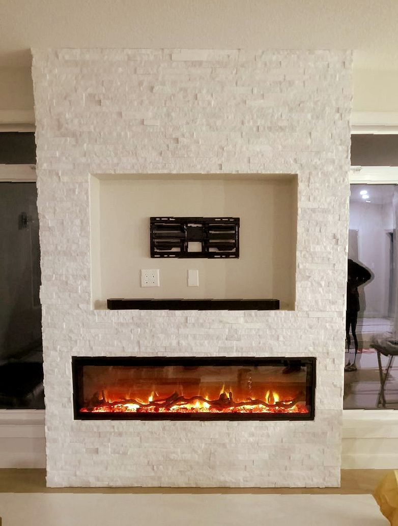 Fireplace with a built-in TV niche and soundbar, set in a white stone wall.