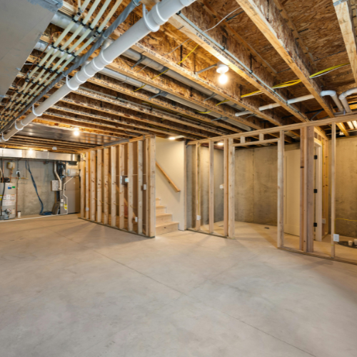 Unfinished basement under construction with exposed ceiling beams, ductwork, framing, and concrete floor