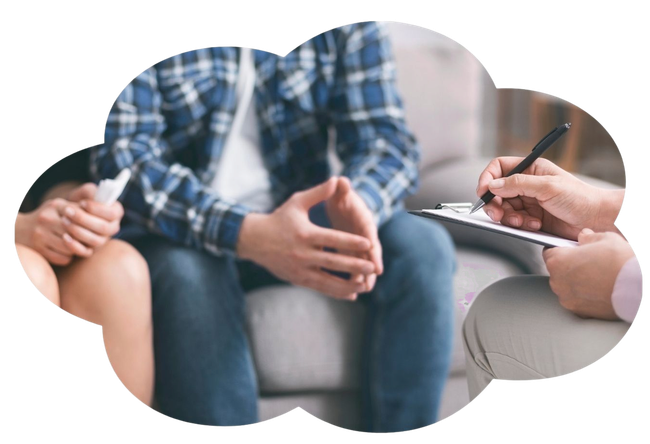 Un terapeuta prende appunti mentre parla con un paziente seduto che tiene in mano una tazza durante una seduta di consulenza.