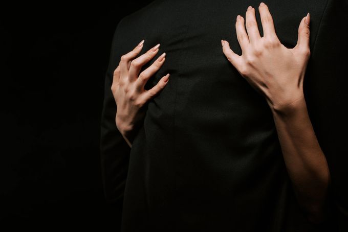 Mani che afferrano la schiena di una persona su uno sfondo scuro