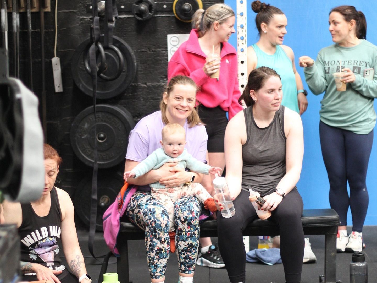 A group of women are sitting on a bench with one woman holding a baby