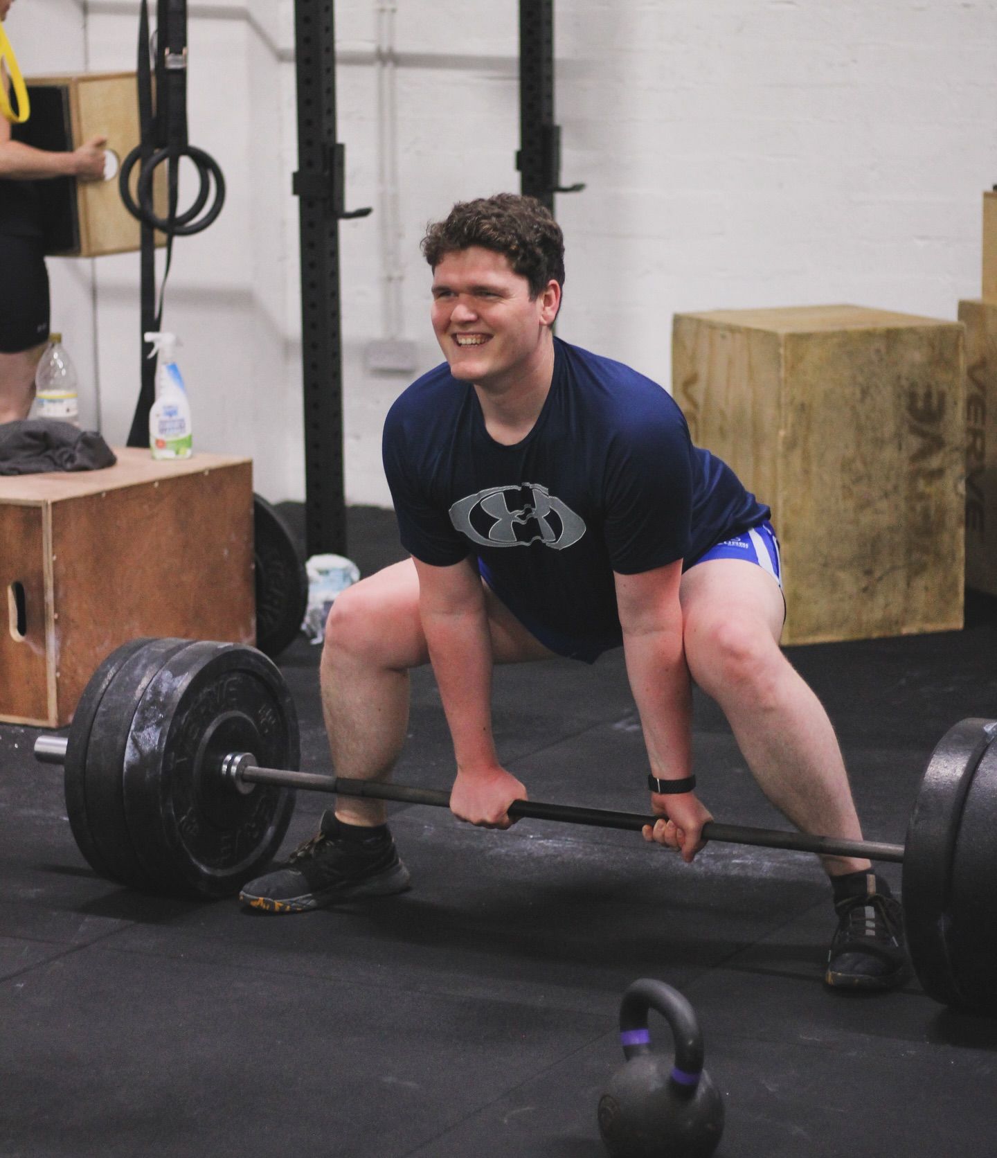 A man squatting down holding a barbell in a gym