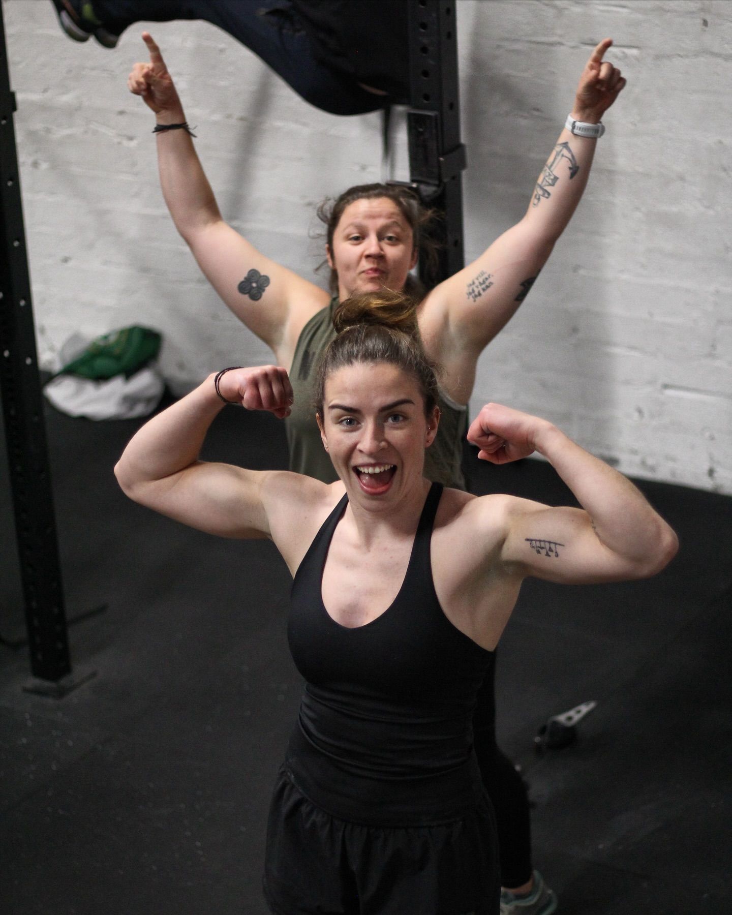 Two women are flexing their muscles in a gym