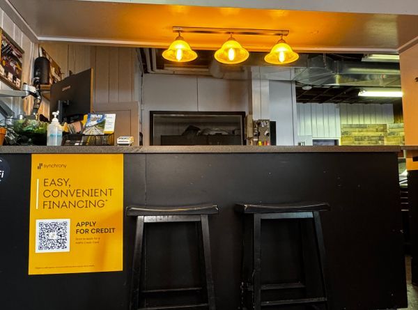 Restaurant counter with black stools, warm pendant lights, and a yellow sign reading “Easy Convenient Financing.” | Exodus Motor Works LLC