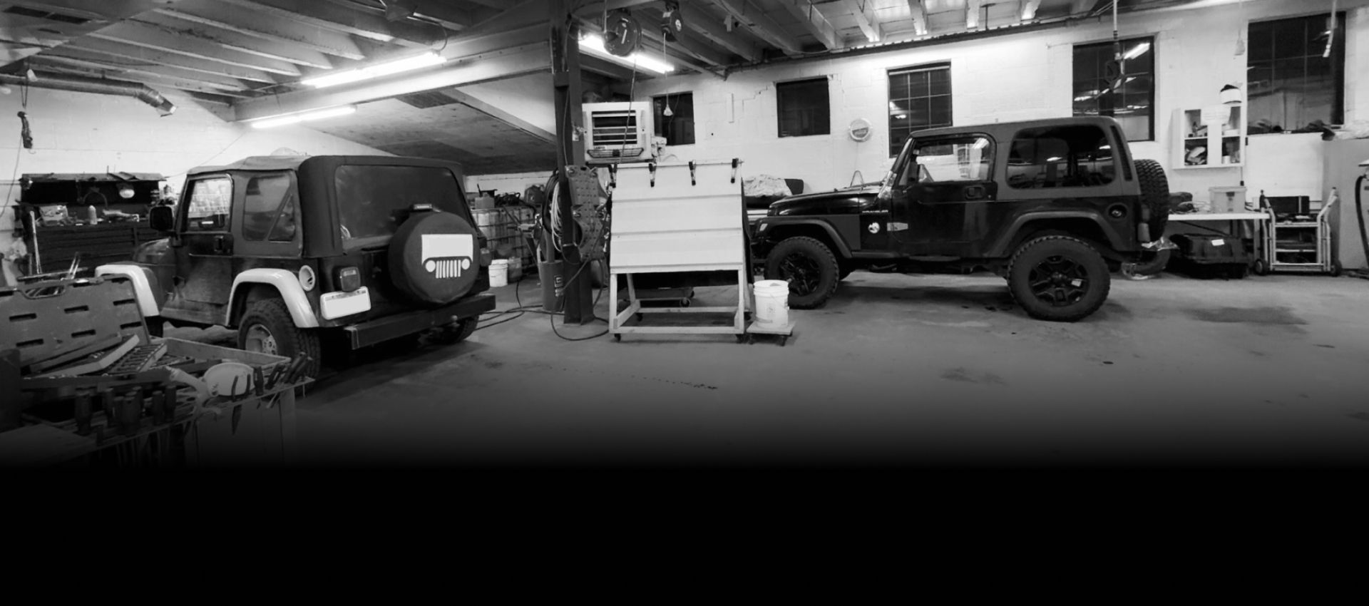 Black-and-white garage with two off-road vehicles and equipment inside a workshop | Exodus Motor Works LLC