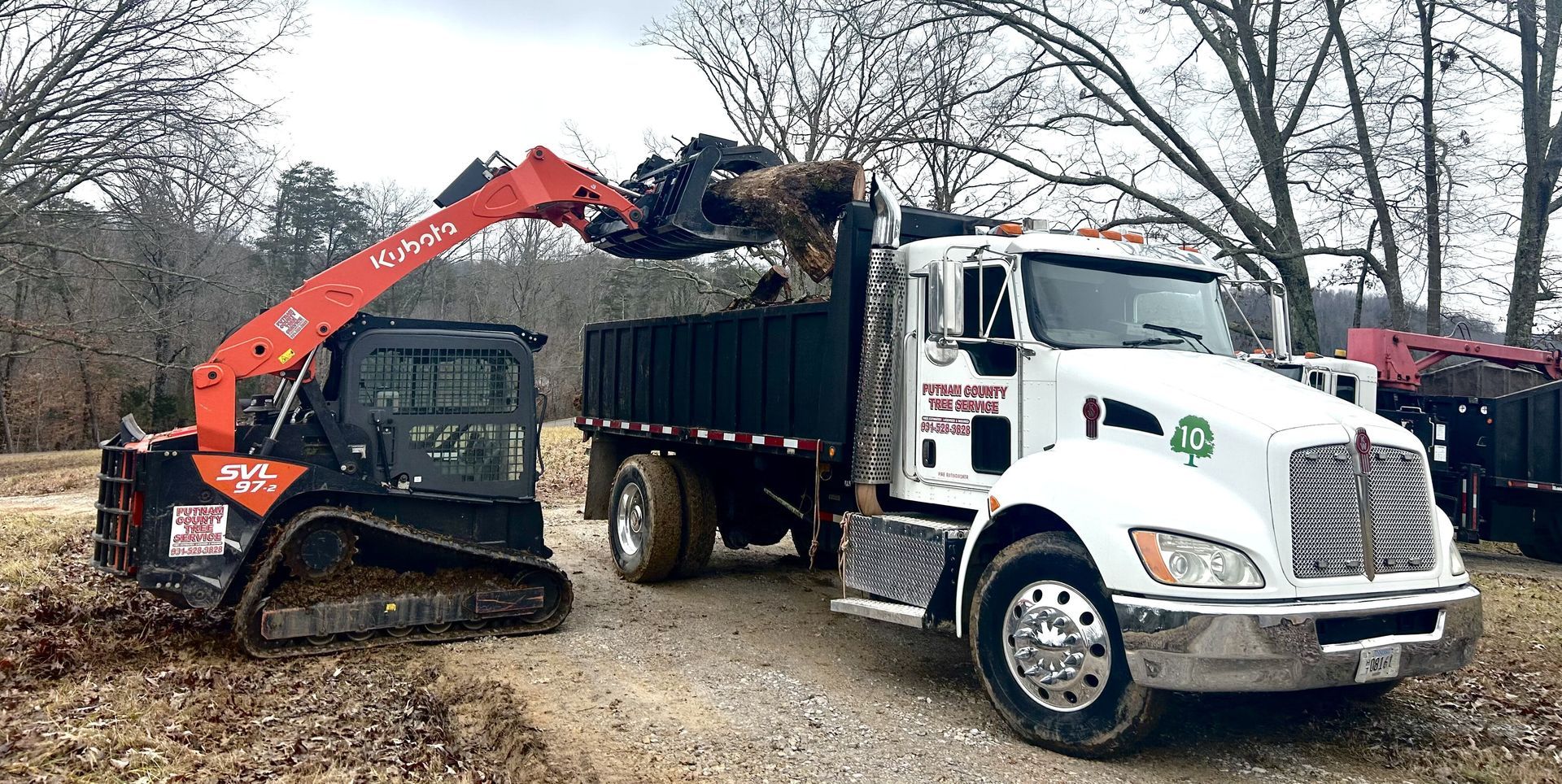 A skid steer loading debris into a white dump truck.